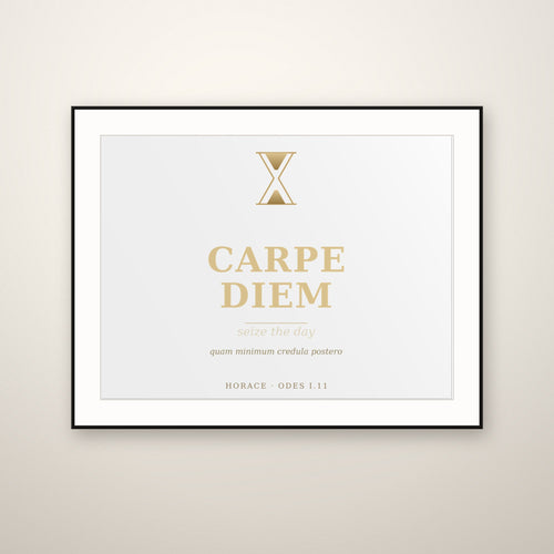 Carpe Diem gold typography print in a thin black frame with a white mat, hung on a warm plaster wall